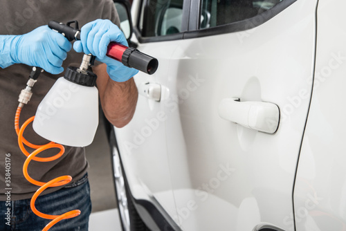 Fotografie Worker cleaning car for virus protection with chemicals