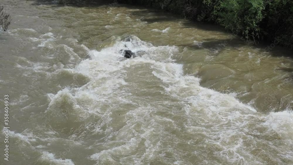 The Serio river swollen after heavy rains. Province of Bergamo, northern Italy. Brown water. The water flows fast from the high valley to the plain The Serio river swollen after heavy rains. Province of Bergamo, northern Italy. Brown water. The water flows fast from the high valley to the plain