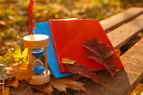 Autumn time theme, Sandglass on fallen leaves in various colors with copy space.