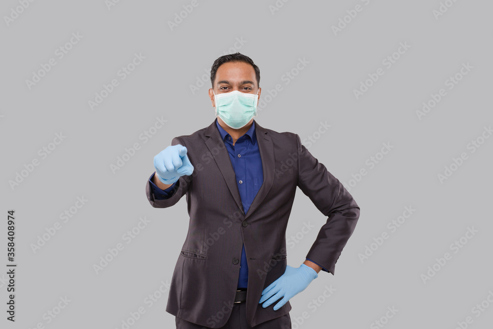 Businessman Pointing Front Watching in Camera Wearing Medical Mask and Gloves Isolated. Indian Business Man Pointing Front Businessman Pointing Front Watching in Camera Wearing Medical Mask and Gloves Isolated. Indian Business Man Pointing Front