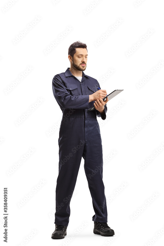 Auto mechanic in a uniform standing and writing a document Auto mechanic in a uniform standing and writing a document