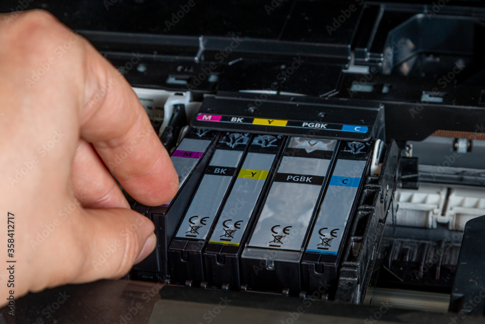 The man changes the ink for the printer The man changes the ink for the printer