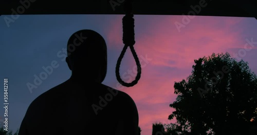 Man Trying to Commit Suicide by Hanging Himself on a Hangman Rope Changing his Mind and Leaving in Silhouette on a Sunset Sky Background a Concept New Life
