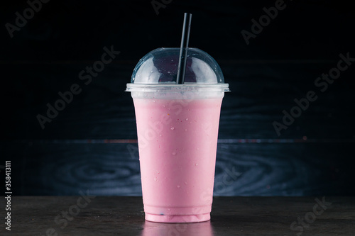 Fotografia cherry milkshake in plastic glass on a dark background