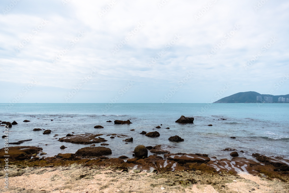 Wild coral beach on a cloudy day with blue water, landscape.