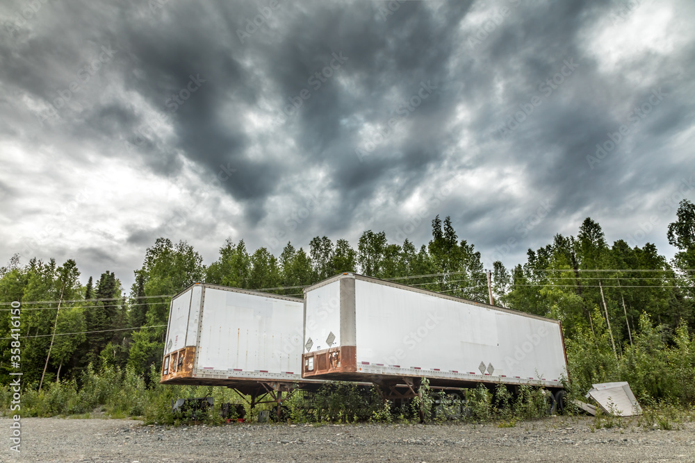 Parked semi-truck trailers on a dirt road in Alaska