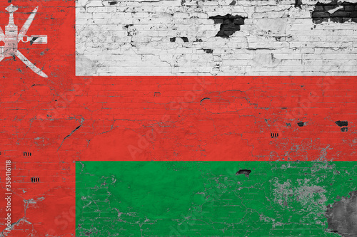 Oman flag on grunge scratched concrete surface. National vintage background. Retro wall concept.