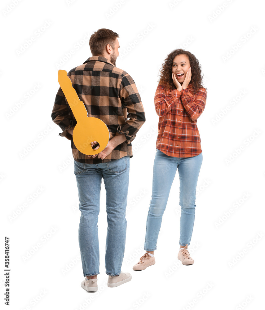 Happy young couple with big paper key on white background