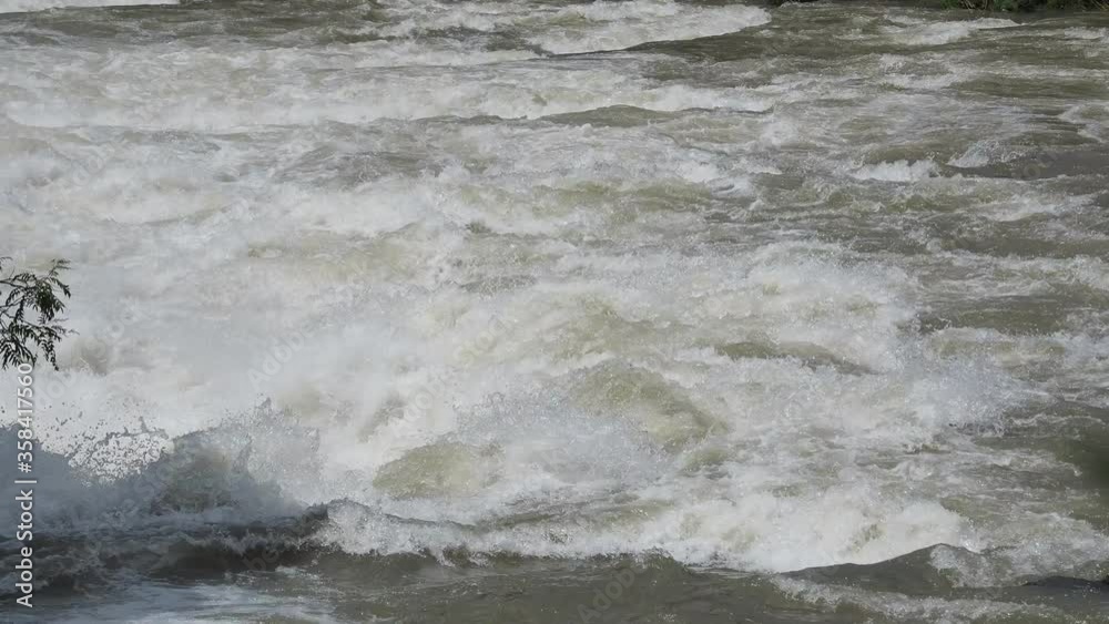 The Serio river swollen after heavy rains. Province of Bergamo, northern Italy. Brown water. The water flows fast from the high valley to the plain The Serio river swollen after heavy rains. Province of Bergamo, northern Italy. Brown water. The water flows fast from the high valley to the plain