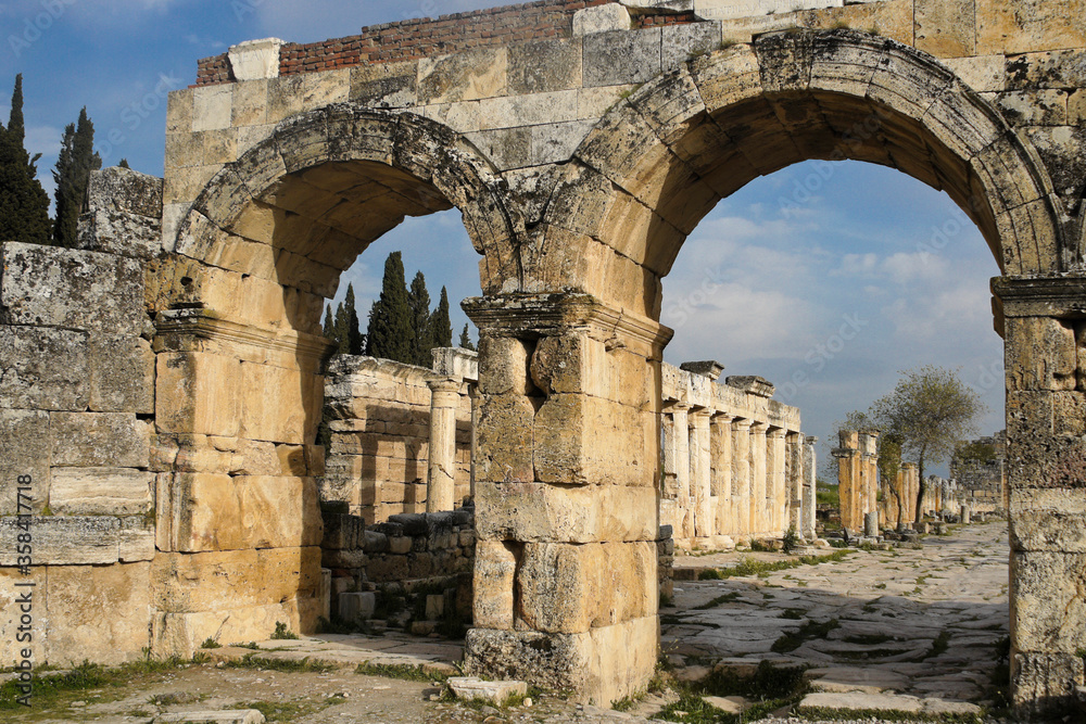 Ruins at the necropolis of the former Roman city of Hierapolis-Pamukkale include tombs, latrines, and gateways such as this arched entrance at the end of a colonnaded stone street.