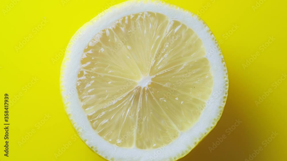 Rotating lemon on a yellow background. Half ripe citrus