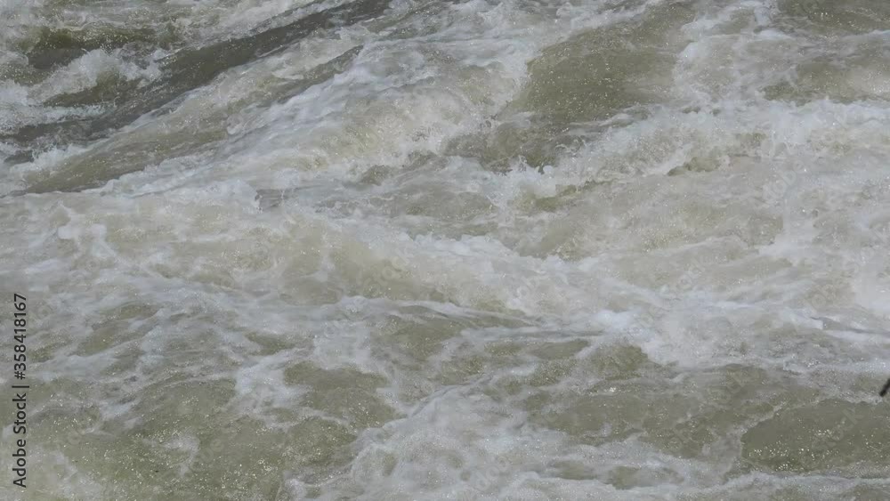 The Serio river swollen after heavy rains. Province of Bergamo, northern Italy. Brown water. The water flows fast from the high valley to the plain The Serio river swollen after heavy rains. Province of Bergamo, northern Italy. Brown water. The water flows fast from the high valley to the plain