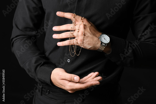 Stylish young man with jewelry on dark background, closeup