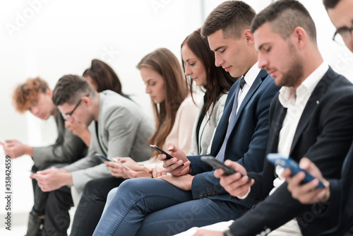 young employees with smartphones sitting in the same row