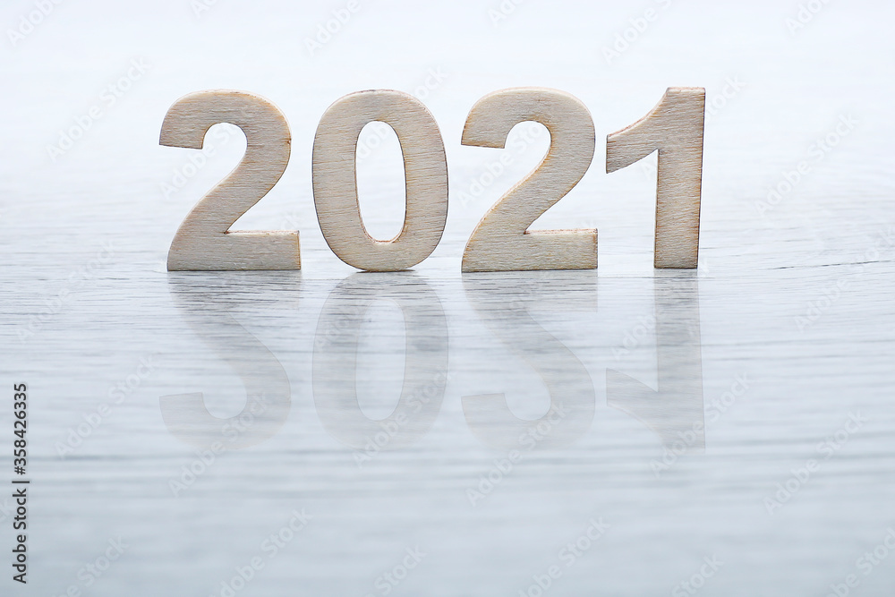 Block letters on 2021 cast shadow on wooden table 