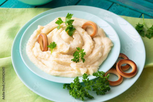 Homemade cream mashed potatoes in a bowl with parsley and russian bublik.