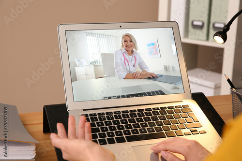 Woman using laptop for online consultation with mature female doctor, closeup