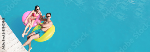 Happy young couple at swimming pool, space for text. Banner design