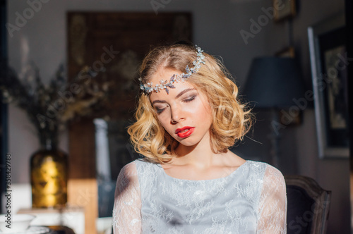 Beautiful blond girl with vintage make up and hairstyle with sunny rays on face and jewelry decoration on head