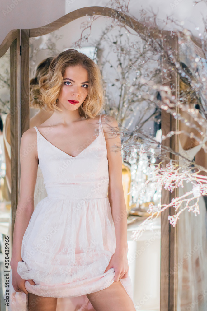 Fototapeta premium Beautiful blond girl with vintage make up and hairstyle staying near mirror