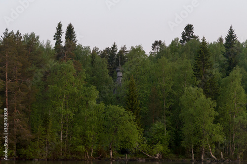 Russia  Karelia  06.07.2019  White nights. Dawn on Lake Muezero. Trinity Monastery on Trinity Island  old wooden church of St. Nicholasin a forest.