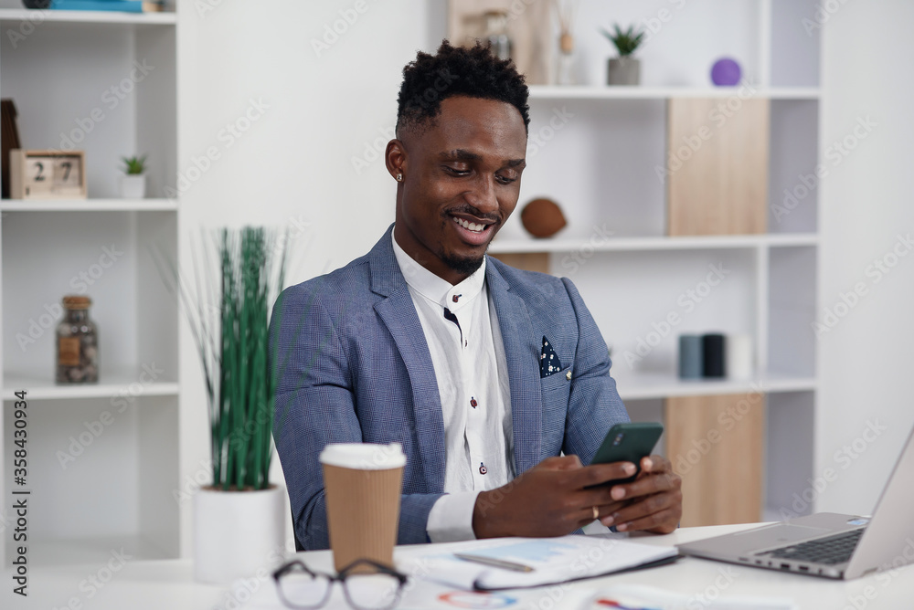 Black businessman surfing internet pages on smartphone, having a break at work in modern office. Black businessman surfing internet pages on smartphone, having a break at work in modern office.