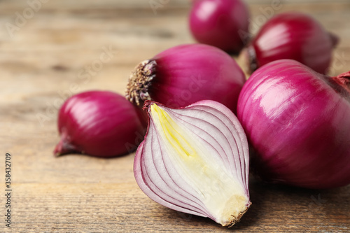 Ripe red onion bulbs on wooden table, closeup