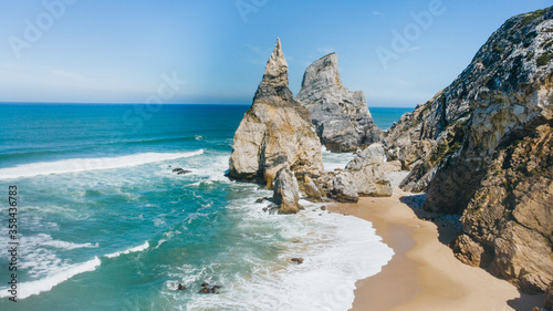 Sand beach among rocks on evening sunset. Ursa Beach near Cape Roca (Cabo da Roca) at Atlantic Ocean coast in Portugal. Summer landscape.