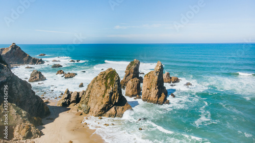 Portugal Ursa Beach at atlantic coast of Atlantic Ocean with rocks and sunset sun waves and foam at sand of coastline picturesque landscape panorama.