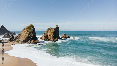 Portugal Ursa Beach at atlantic coast of Atlantic Ocean with rocks and sunset sun waves and foam at sand of coastline picturesque landscape panorama.