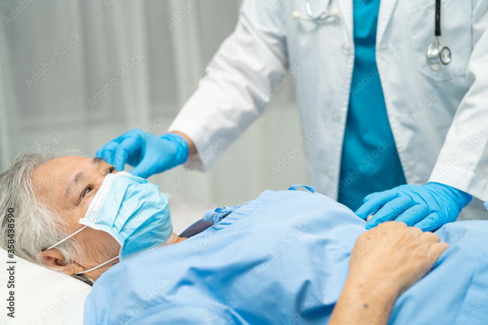 Doctor help Asian senior or elderly old lady woman patient wearing a face mask in hospital for protect safety infection and kill Novel Coronavirus Covid-19 virus..