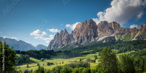 Mountains with alpine village on sunny summer day, the Dolomites Mountains, Italy