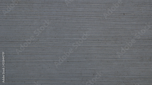 Background texture of concrete with textured brushed finish. Light gray brush concrete texture. Concrete pavement. Gray cement slab texture