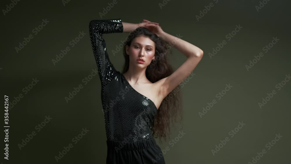 A young beautiful sensual female model poses on a dark green background. Fashion shooting in the studio. A young beautiful sensual female model poses on a dark green background. Fashion shooting in the studio.