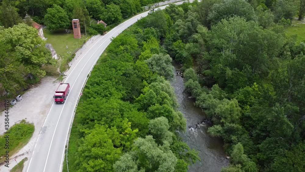 Red truck and car passing on traffic road next to river . Aerial view Red truck and car passing on traffic road next to river . Aerial view
