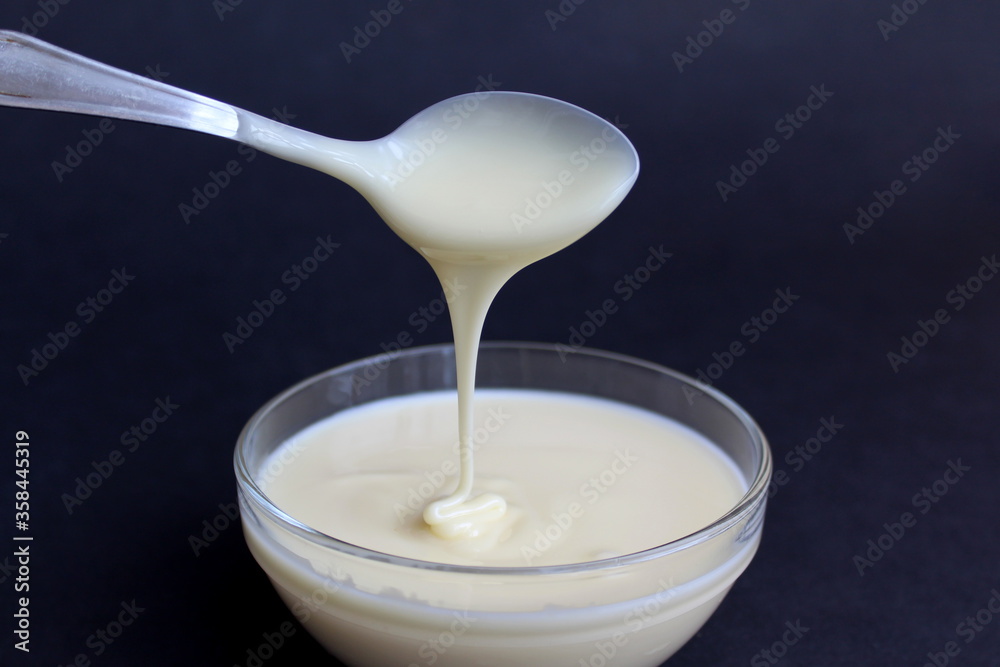 Condensed milk from a boat drains into a glass plate Condensed milk from a boat drains into a glass plate