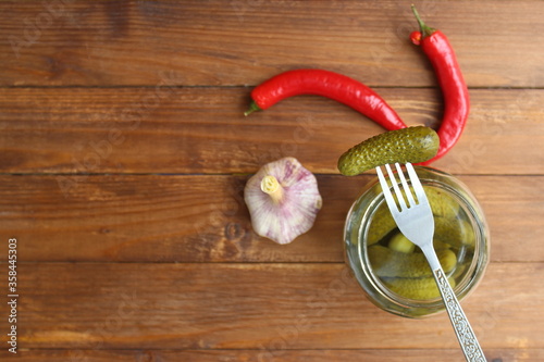 Glass jar with pickled cucumbers and one strung on a fork, top view photo