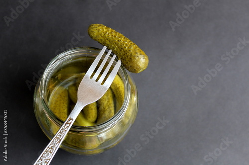Glass jar with pickled cucumbers and one strung on a fork