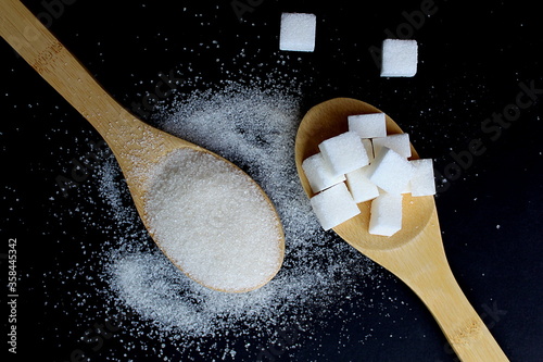 Friable sugar on a wooden spoon on a black background photo