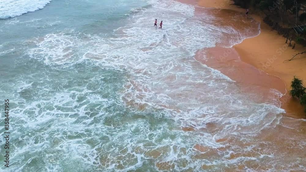 Young traveler friends walking in waves on empty beach in Sri Lanka Young traveler friends walking in waves on empty beach in Sri Lanka