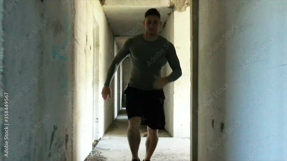 Male athlete running in corridor of abandoned building Male athlete running in corridor of abandoned building