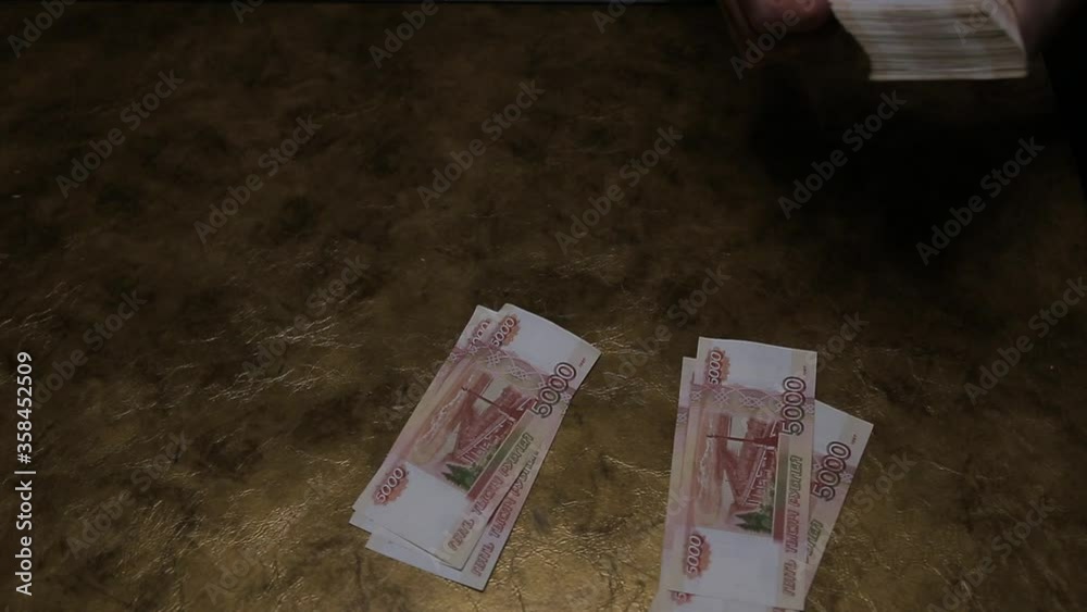 A person counts Russian five-thousand-dollar bills and puts them on the table.