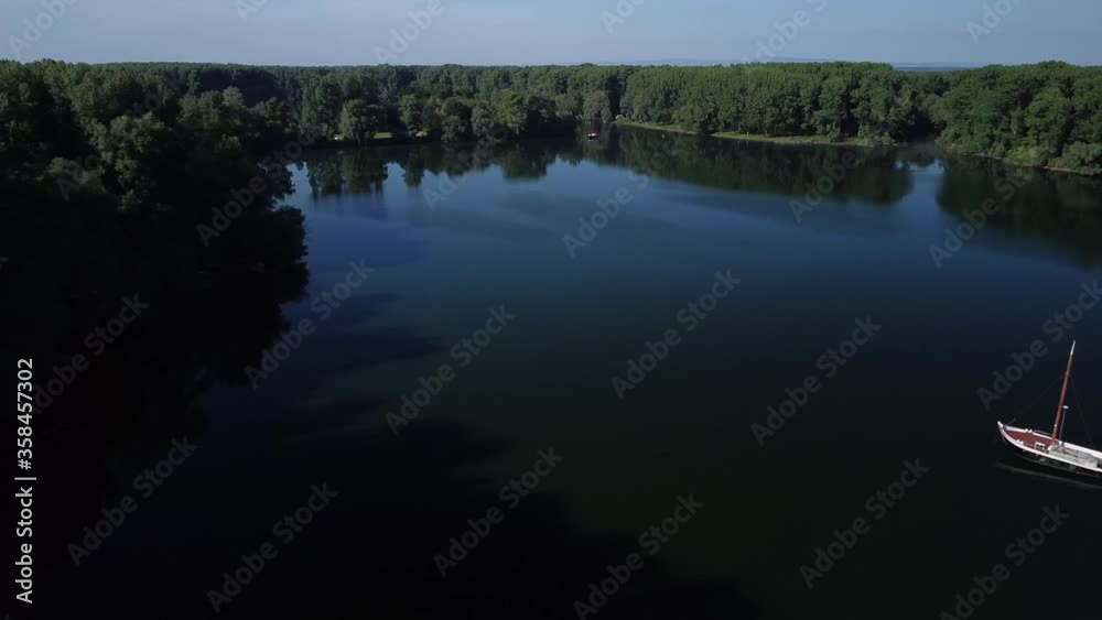 Drone flying sideway until yacht comes into view on a quiet river in Germany at sundown Drone flying sideway until yacht comes into view on a quiet river in Germany at sundown