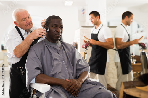 African man getting haircut from elderly barber