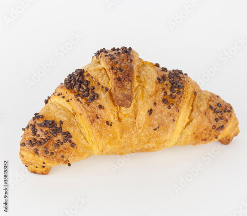 A french croissant filled with hazelnut and covered with chocolate nuggets on white background. French pastry.