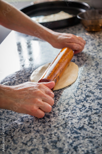 Vertical shot of Moroccan flat bread pancakes preparation on a kitchen table with chef woman hands kneading the oily squared shapes. Traditional Moroccan gastronomy breakfast stills with copy space. photo