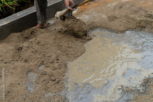 Indian labour mixing cement and water manually on floor using a shovel. Stock image.