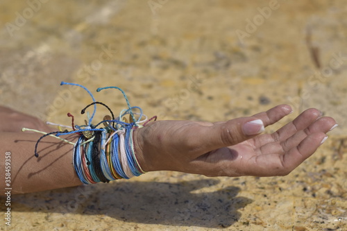 woman hands with colorful bracelets touching the water on the shore of the pool