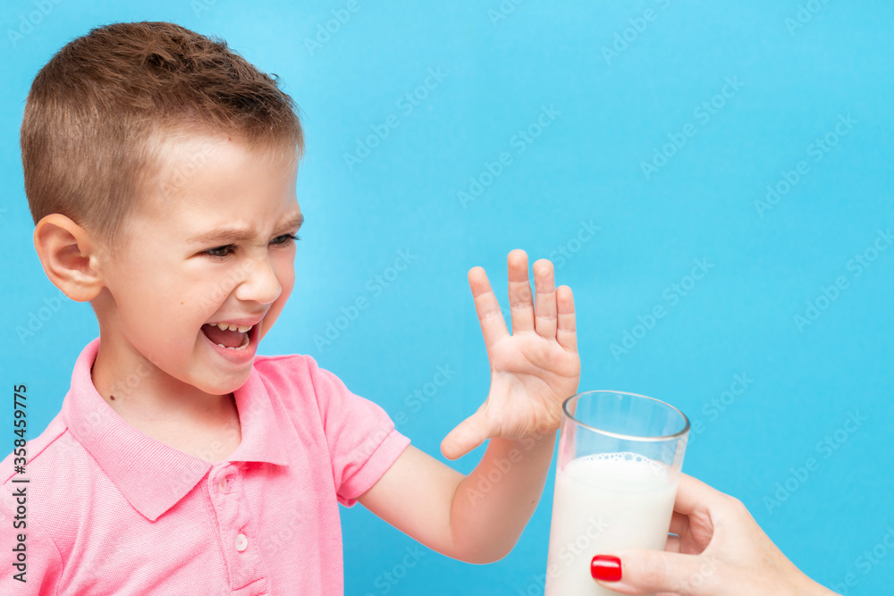 Sad harmful little kid refusing to drink milk showing stop gesture Sad harmful little kid refusing to drink milk showing stop gesture
