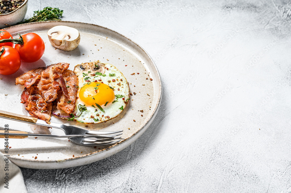 Plate of fried eggs with bacon and fresh tomato, mushroom. Breakfast set. White background. Top view. Copy space